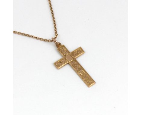 An early 20th century 9ct gold cross pendant, the scrolling engraved front with plain polished reverse, 4.5cm long, upon an a