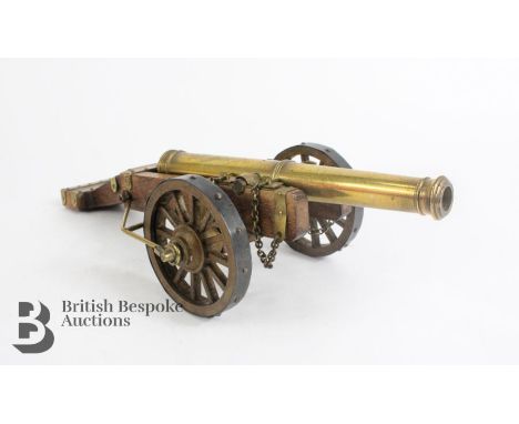 Oak and brass desk canon, with brass barrel 16 cms in length, two metal-clad wheels and brass furniture to an oak frame, tota