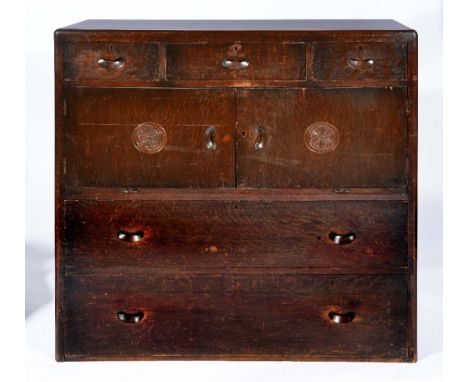 Maples oak chest having three short drawers over cupboard sections decorated with circular flower motifs over two further lon