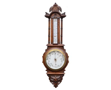 An Edwardian aneriod wall barometer  with ceramic dial and mercury tube thermometer over within a carved oak case with turned
