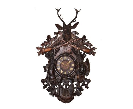 A large Black Forest cuckoo clock the carved case with stags head pediment supporting a pair of sporting guns over hanging de