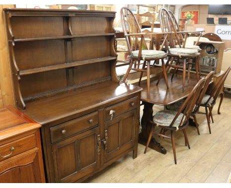 An Ercol dark-stained elm dining suite, comprising table, six chairs and a dresser table W.152cm