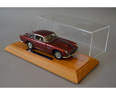 An unboxed  Danbury Mint diecast model  of a 1964 Aston Martin DB5 in 1:24  scale together with  wooden plinth and perspex co