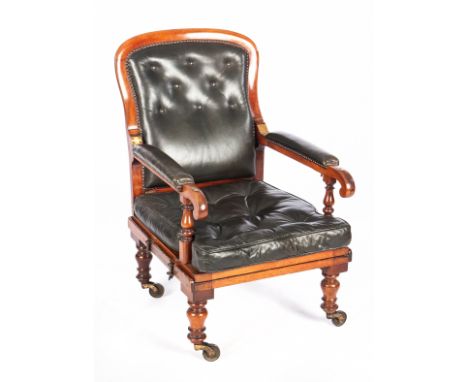 The moulded frame with buttoned leather back, the hinged arms with leather pads on turned and ring-turned legs with large cas