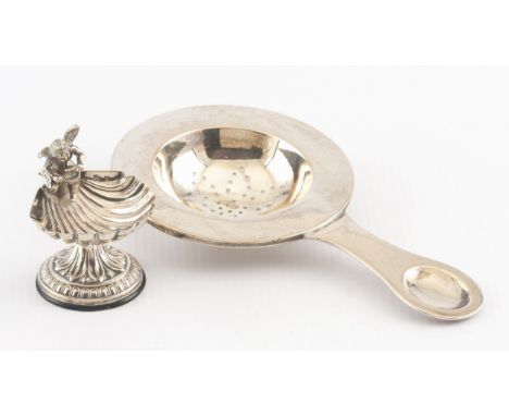 The first 875 standard, with plain broad everted rim, spoon-shaped handle, 65g, the salt designed as a putto seated beside a 
