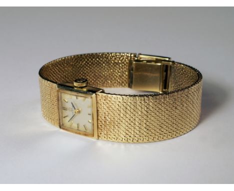 A 9ct gold cased Omega ladies manual wind wrist watch, 1968, with square silvered dial, gold batons and integral textured mes