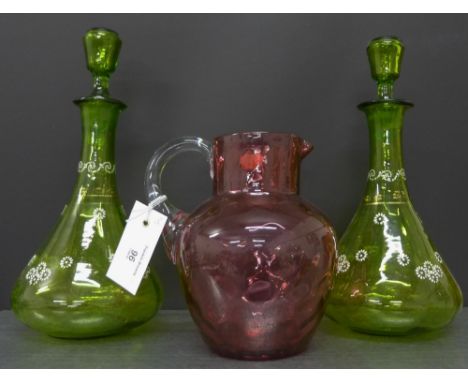 A pair of green glass and enamel decorated decanters and stoppers together with a dimple cranberry glass jug (3)