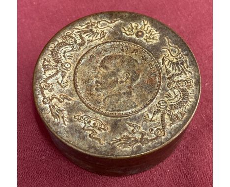 A circular bronze scroll weight with dragon detail to top rim.  Approx. 3cm tall x 7.5cm diameter.