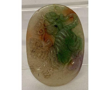 A carved jade oval shaped pendant featuring a tiger.  Approx. 6cm x 4.25cm.