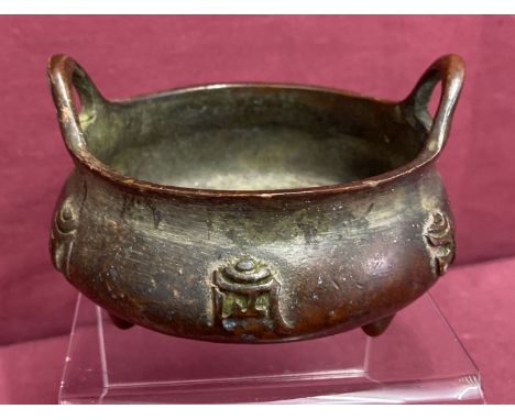 A small bronze 2 handled censer, raised on tripod feet &amp; with calligraphy detail to outer bowl. With loop handles, signed