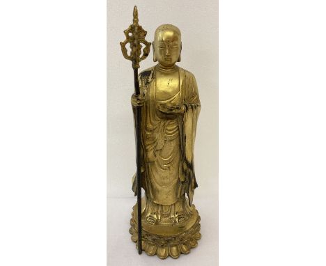 A gilt hollow bronze figure of an Oriental Deity holding a staff stood atop a lotus flower. Leaf mark to underside. Approx. 2