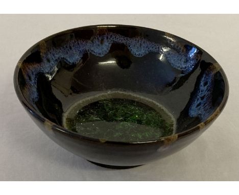 A small black glaze ceramic tea bowl with drip glaze detail &amp; green crystalline glaze to inner bowl.  Approx. 4.5cm tall 
