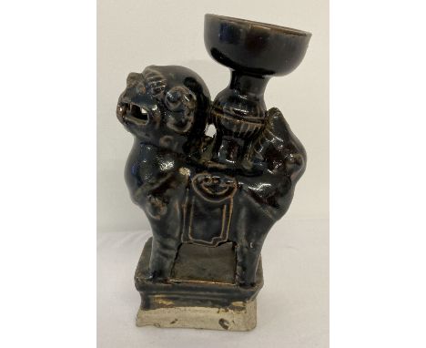 A Chinese stoneware ceramic candle holder in the form of a foo dog, with black glaze.  Approx. 18cm tall.