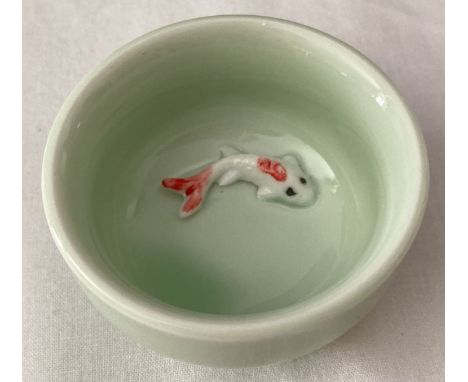 A small pale green glazed ceramic bowl with fish detail, in relief, to base of interior.  Approx. 3.5cm x 6cm diameter.