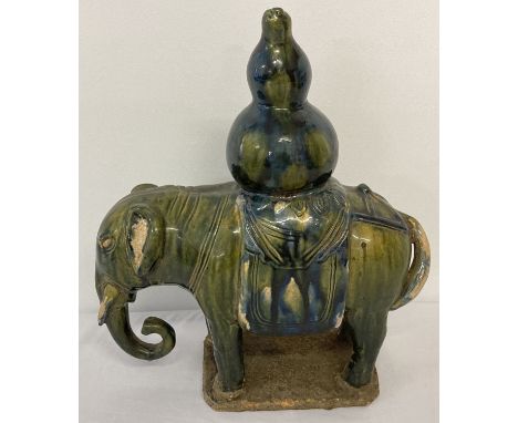 A stoneware ceramic elephant figurine carrying a gourd, in blue/green majolica style glaze.  Approx. 33cm tall x 28cm long.