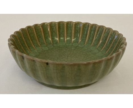 A small round ceramic dish with scalloped rim and dark green crackle glaze.  Approx. 13cm diameter.