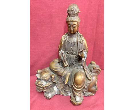 A Chinese bronze figurine of an Oriental Deity sitting atop a foo dog. Impressed signature marks to base. Some corrosion to m