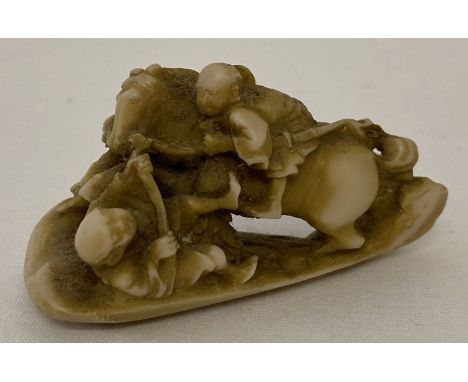 A small carved netsuke depicting 2 men in confrontation; one on horseback.  Approx. 3.5cm tall x 6.5cm long.