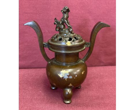 A decorative lidded bronze censer with gold splash detail. Raised on tripod feet, with pierced work detail to lid and foo dog