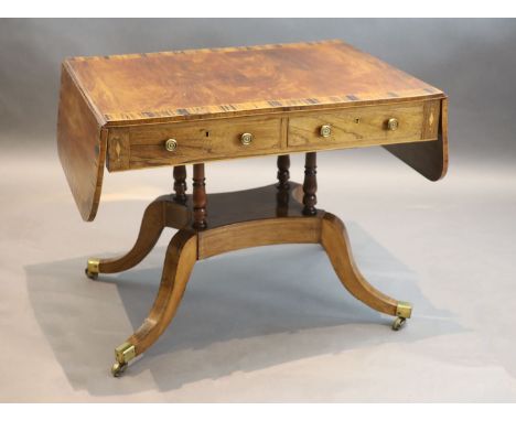 A Regency mahogany sofa table banded in coromandel, with d shaped flaps and two frieze drawers, on four column stem with down