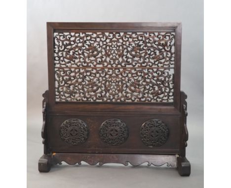 A large Chinese hardwood table screen, c.1910, the inset screen profusely carved and pierced with scrolling chi-dragons, the 