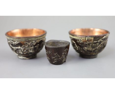 A pair of Chinese coconut 'landscape' cups and a similar peach-shaped cup, 18th/19th century, the pair each carved in high re