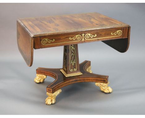 A Regency brass inset rosewood sofa table, the top with D shaped flaps inlaid with a band of scrolling foliage, over two frie