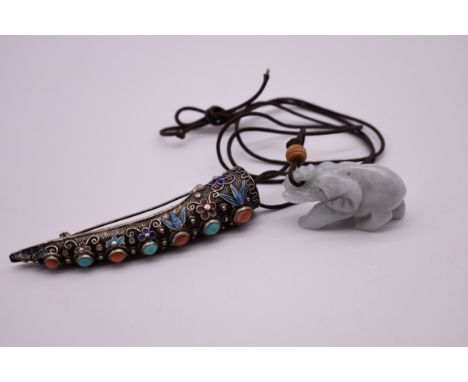 A Chinese silver filigree and enamel finger claw brooch, 8.5cm long; together with a carved celadon jade elephant pendant, 4.