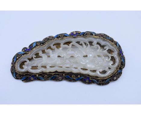 A Chinese carved and pierced celadon jade brooch, set in silver gilt filigree and enamel mounted, 8.2cm wide. 