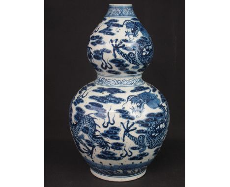 19TH CENTURY CHINESE PORCELAIN DOUBLE GOURD VASE decorated with scaly dragons within clouds, blue and white with wave and scr