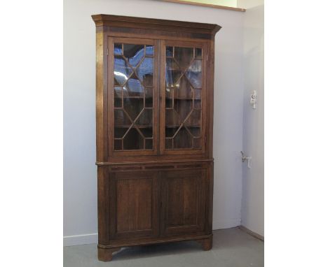 LATE GEORGIAN WELSH OAK DOUBLE STANDING CORNER CUPBOARD having moulded cornice over mahogany veneered frieze, pair of astraga