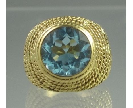 A YELLOW METAL RING SET WITH LARGE BLUE TOPAZ. The mixed cut blue topaz in heavy gold rope work mount. Ring size I. Weight 15