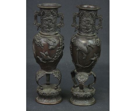 PAIR OF 20TH CENTURY JAPANESE BRONZE TWO HANDLED BALUSTER VASES raised on tripod legs and circular pedestal base. Relief deco