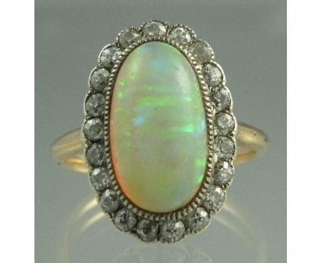 A VICTORIAN OPAL AND DIAMOND DRESS RING. The large oval opal an estimated 15mm x 18mm surrounded by twenty-one old cut diamon