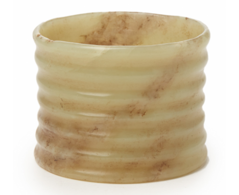 A CELADON AND RUSSET JADE CARVING In the archaistic manner, of waisted cylindrical form with ribbed exterior 7.5cm diameter, 