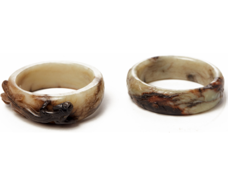 TWO CARVED WHITE AND RUSSET JADE BANGLES In the archaic Zhou style One with a stylised dragon in high relief; the other with 