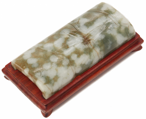 A MOTTLED JADE BAMBOO FORM WRIST REST The stone of grey, green and russet tones, with carved bamboo decoration On wood stand 