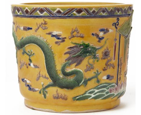 A YELLOW GROUND BISCUIT JARDINIERE Decorated in relief with two trailing green dragons amongst clouds on a yellow ground in t