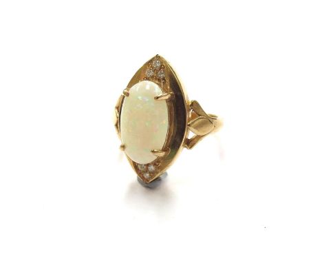 A gold ring with central oval opal in four claws raised on a wide lozenge outer, set north and south with three brilliant cut