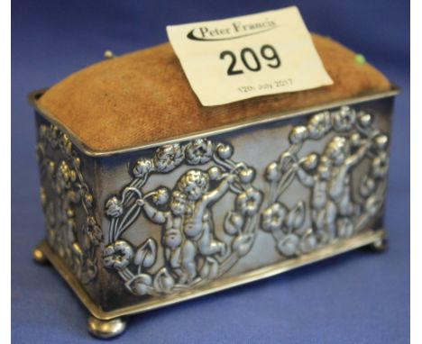 Silver rectangular Art Nouveau pin cushion, repousse decorated with children within floral and leaf borders, raised on four b