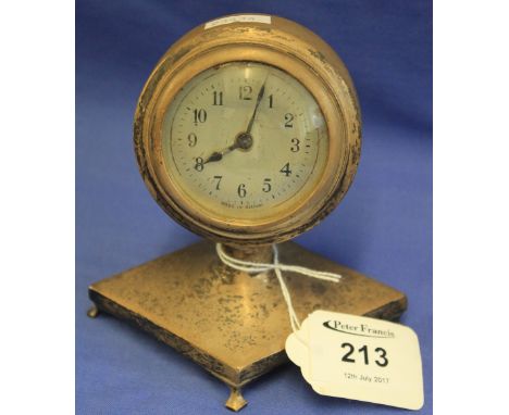 Small silver desk clock with circular head raised on diamond design base, on four splayed feet.  Birmingham hallmark.(B.P. 24