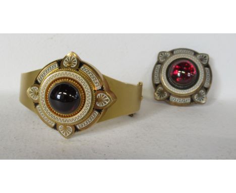A Victorian pinchbeck hinged bangle, in the Etruscan Revival style, set with cabochon garnets, and white enamel decoration, t