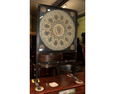 A 19th century ebonised firescreen, with glazed panel enclosing an 18th century silk work panel 