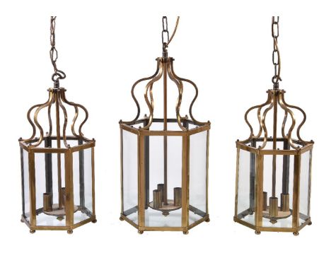 A pair of gilt metal and glazed three-light hexagonal hall lanterns in George III style, 20th century, each with six scrolled