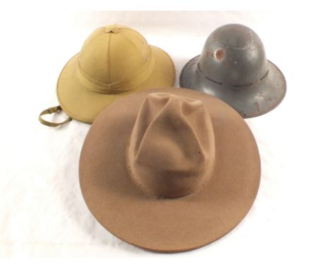 A Royal Canadian mounted Police hat (1962) with a WWII Civil Defence helmet (dated 1941) and a pith helmet