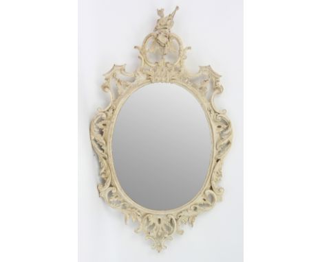 A carved limewood and painted rococo mirror, the frame carved with scrollwork rocaille and topped with an Oriental musician, 