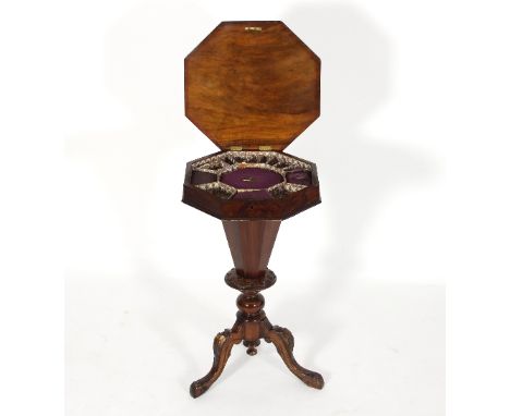 A Victorian walnut octagonal work table with inlaid hinged cover and fitted interior, having a tapered basket on a carved tri