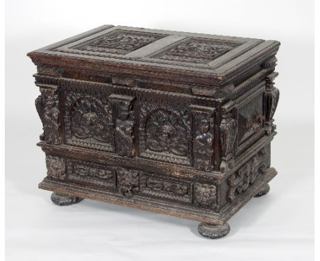 A 17th Century style oak chest, the hinged cover with two armorial carved panels, the front with two arched panels centred by