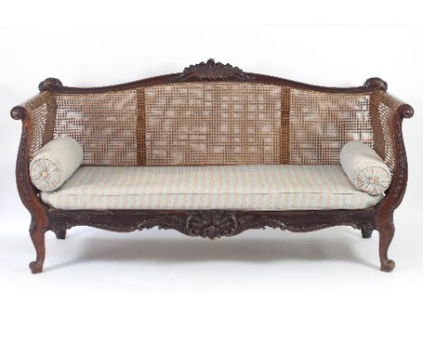 A Louis XV style walnut and caned canape, circa 1880, the serpentine back with a rocaille shell above a caned panel, husk car