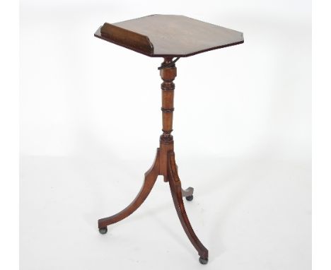 A Regency mahogany reading table, with ebonised banding, with tilt top and rest on a turned column and tripod support, the to